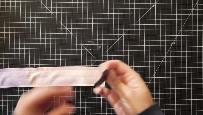 Assemble the strap correctly (see video for detailed instructions). This step involves feeding the strap and bracket pieces through the D-ring and securing everything by sewing.