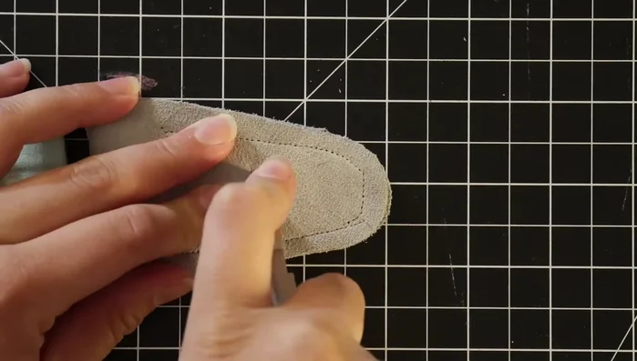 Cut holes (or a slit) in the leather for attaching to the guitar.