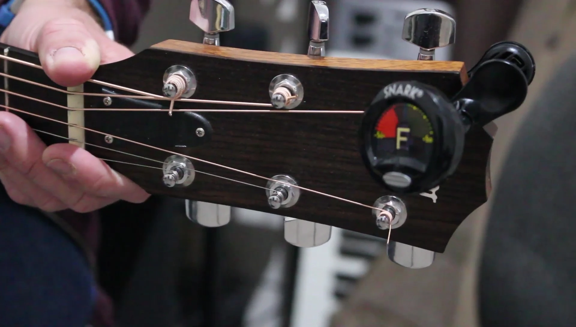 The tuner is shown on a guitar headstock, emphasizing its compact design.