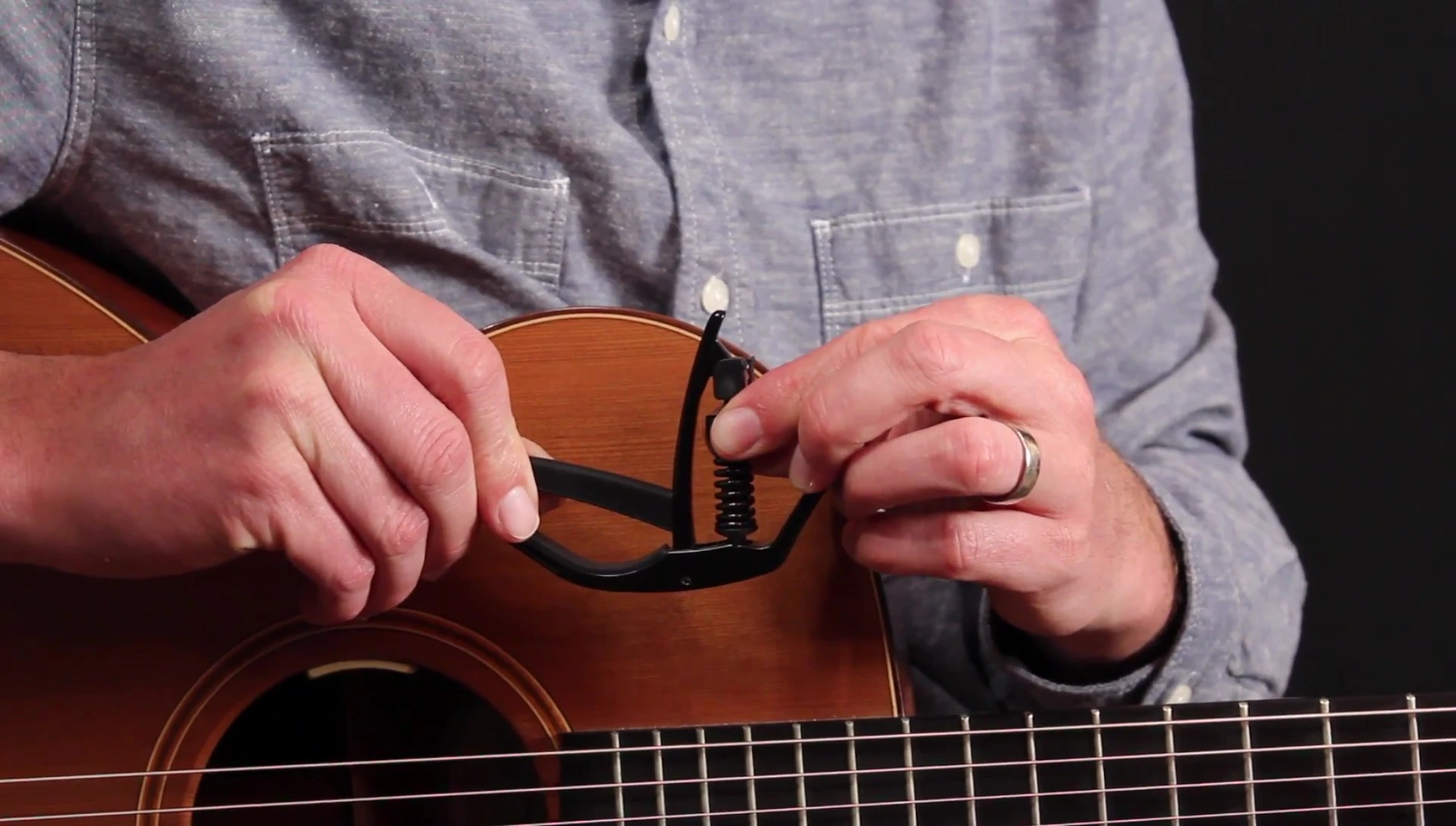 Hand adjusting the tension dial on the capo
