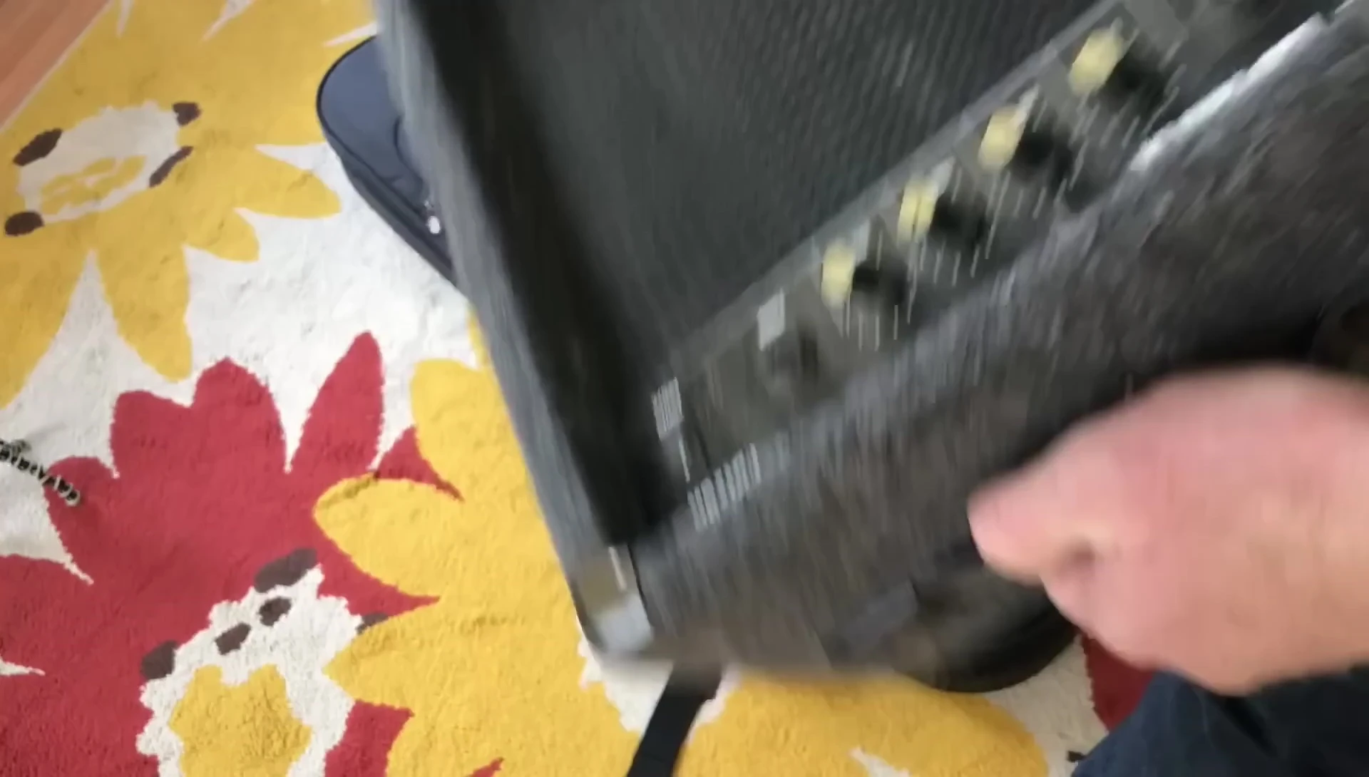 The smaller amp being held high above the guitar case, prepared for the drop test.