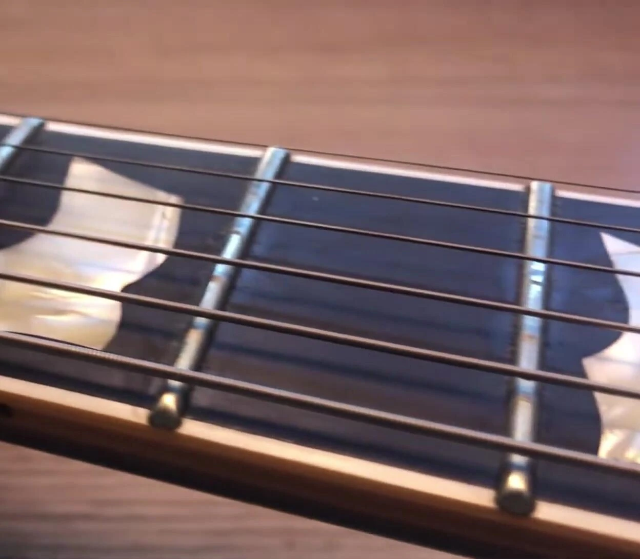 The PRS guitar fretboard showing less grime compared to the Ernie Ball guitar.