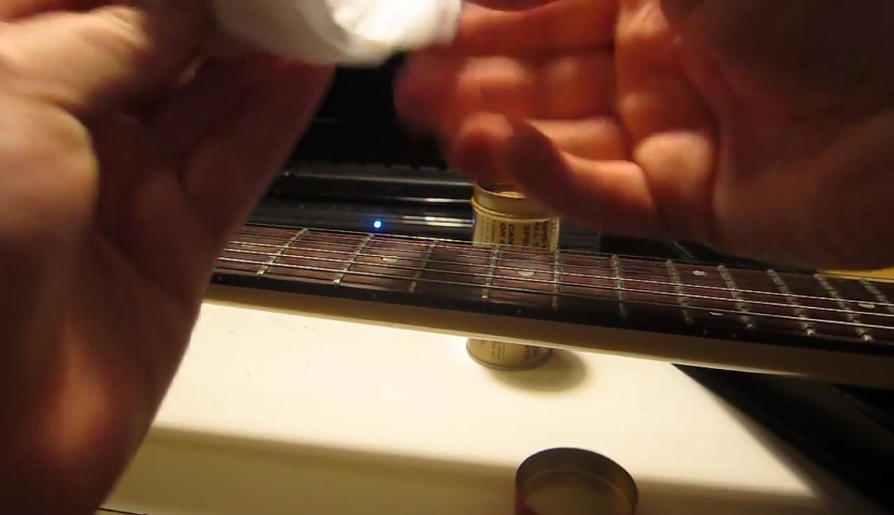 Close-up of dirty guitar strings and fretboard before cleaning.
