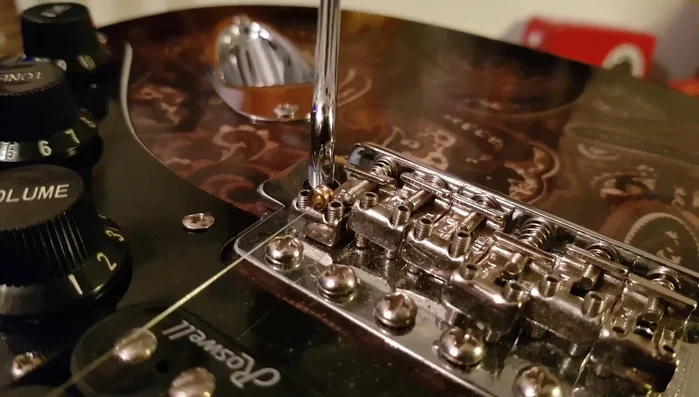 Hold the ball end down with your finger until the string's downward force holds it in place.