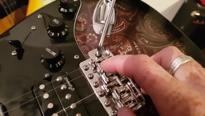 Hold the ball end down with your finger until the string's downward force holds it in place.