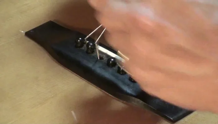 After lifting the pin, shove the string down to loosen it further and remove it with fingers.