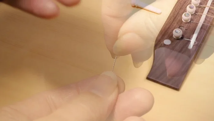 Take the new string and slightly bend the ball end ([248.48]). This prevents the string from slipping off the tuning peg and potentially causing injury. 