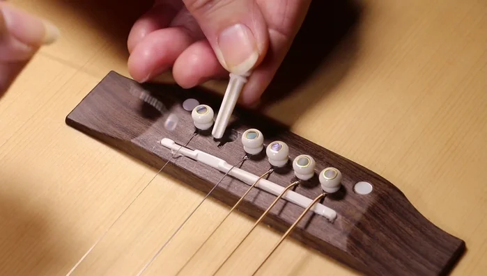 Insert the string into the tuning peg, ensuring it sits correctly in the groove ([309.84], [312.72]). Wind the string onto the tuning peg in the correct direction. For most guitars, left-hand pegs are wound counterclockwise and right-hand pegs clockwise ([325.759], [346.72]). Wind the string a few times to secure it ([424.08]).