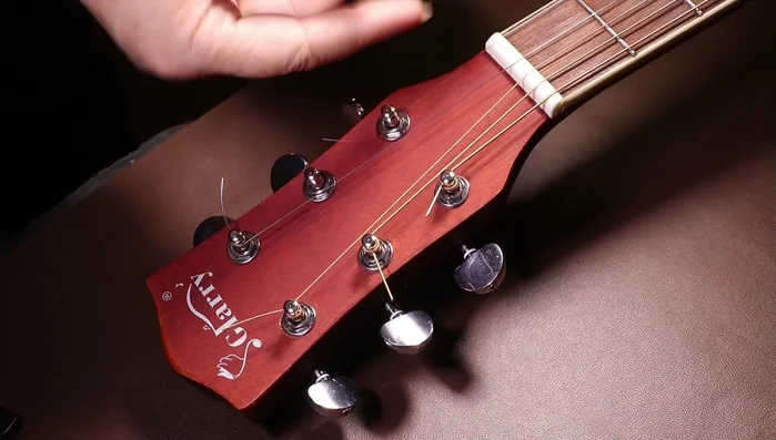 Insert the string into the tuning peg, ensuring it sits correctly in the groove ([309.84], [312.72]). Wind the string onto the tuning peg in the correct direction. For most guitars, left-hand pegs are wound counterclockwise and right-hand pegs clockwise ([325.759], [346.72]). Wind the string a few times to secure it ([424.08]).