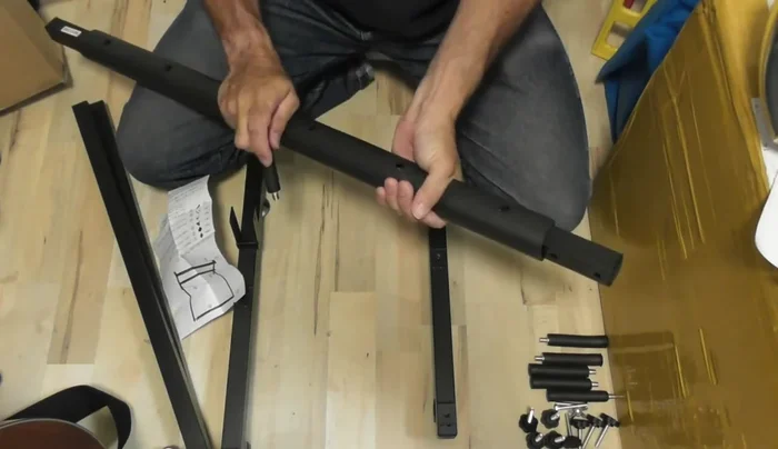 Attach the two upright support pieces to the base pieces using the pegs. Note that the included plastic caps might spin freely; applying pressure to the center metal piece while turning is necessary to secure them.