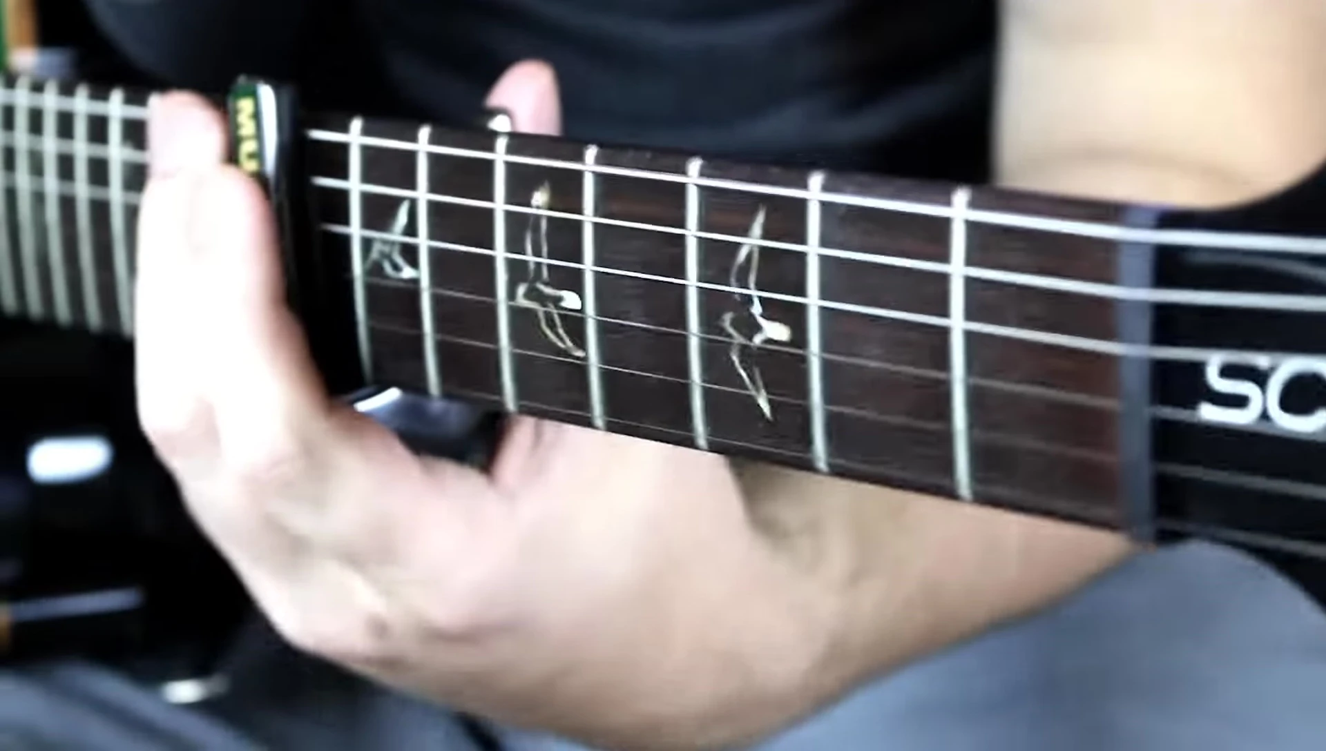 The capo resting on the nut of the guitar