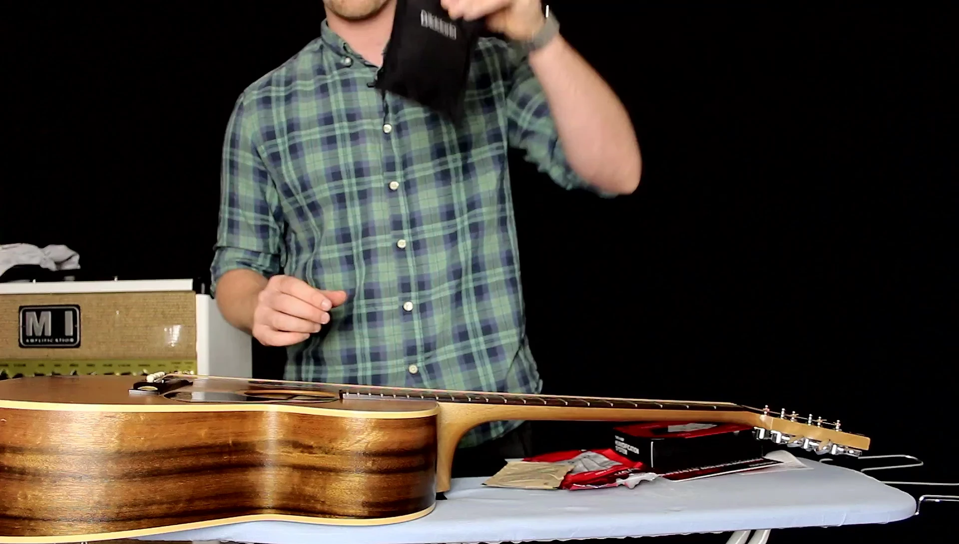 Inserting the pouch into the sound hole of the acoustic guitar.