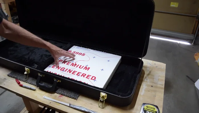 Carefully cut out the traced shape from the foam insert, ensuring the cut is slightly inside the traced line for a precise fit. Use a spray paint can wrapped in sandpaper to gently shape the neck contour on the foam.