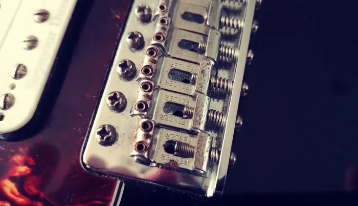 Disassemble the guitar bridge to access the rusty parts.