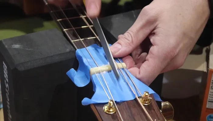 Check if the string sits correctly in the groove. If it's too high, carefully file the nut slot down to the correct height.