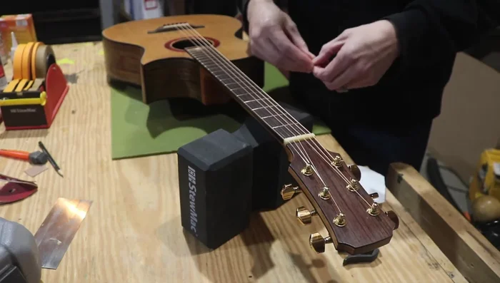 Test for nut slot issues using a piece of paper. Place folded paper under the buzzing string at the nut. If the buzzing reduces, the nut slot is likely too low.