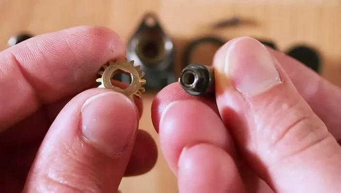 Reinsert the gear, ensuring the flat side is around the bottom of the peg and the indented side holds the screw head. Tighten the screw through the gear into the peg.