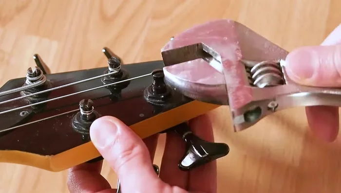 Fit a wrench to the nut on the top of the tuner and remove the stem, washer, and tuning peg.