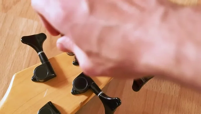 Access the screw by carefully removing the cap on the back of the tuner. If the peg won't thread, use the wrench to gently tap the screw head, driving it into the cap and removing the cap.