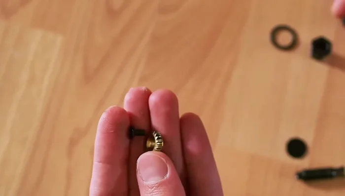 Reinsert the gear, ensuring the flat side is around the bottom of the peg and the indented side holds the screw head. Tighten the screw through the gear into the peg.