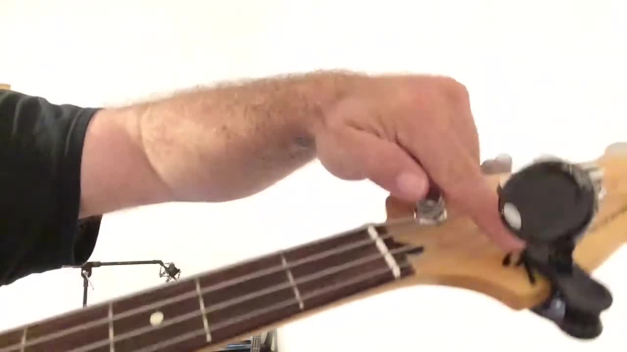 Close-up of the Snark tuner being placed on the Fender logo of the bass guitar.
