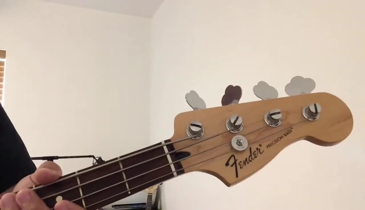 The Snark Super-Tight tuner being positioned on the bass guitar.