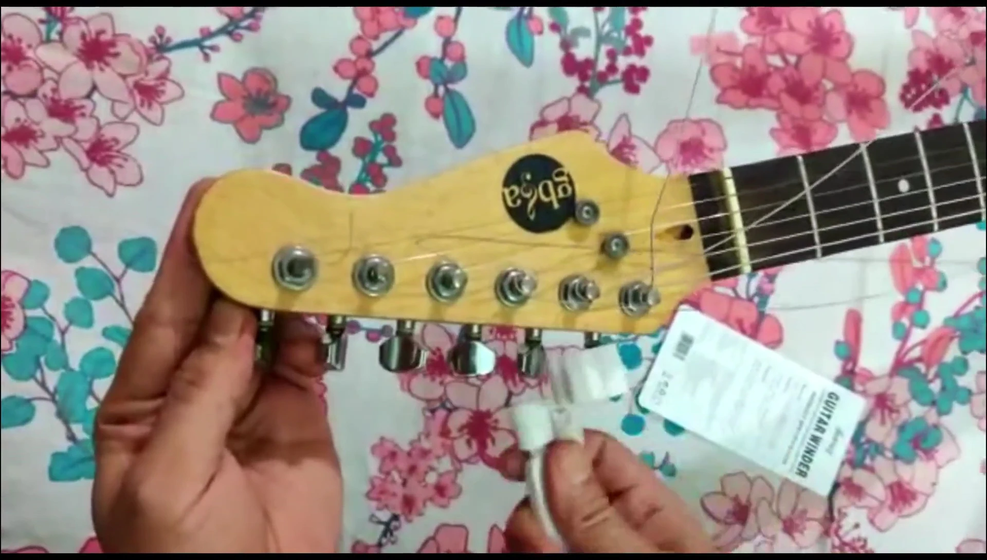 The reviewer using the tool to cut a guitar string