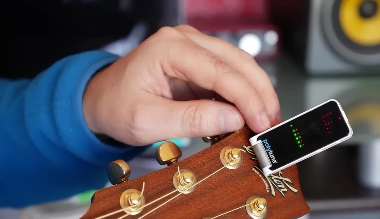 Reviewer using a pick to strum the guitar.