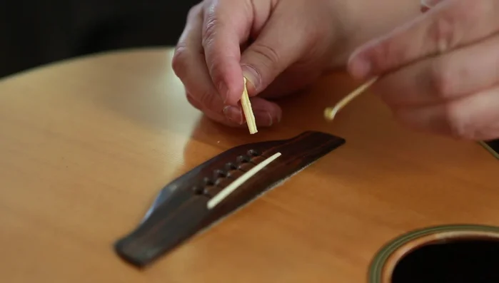 Seat new strings in the bridge pin slots, with the ball end underneath.