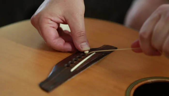 Tighten strings, pushing down on the bridge pin if needed to prevent it from lifting.