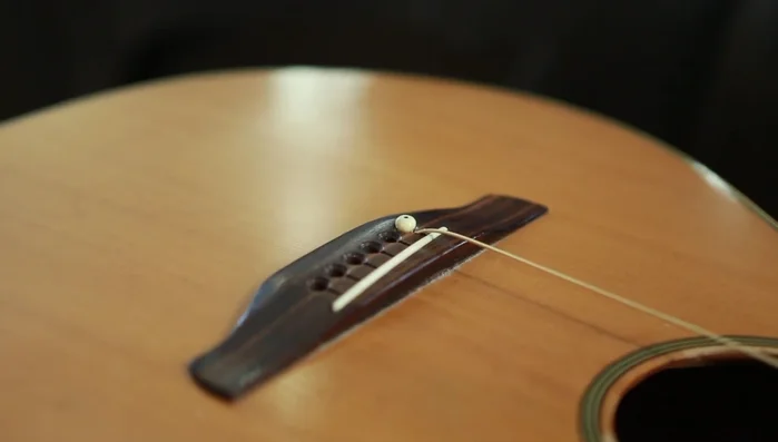 Tighten strings, pushing down on the bridge pin if needed to prevent it from lifting.