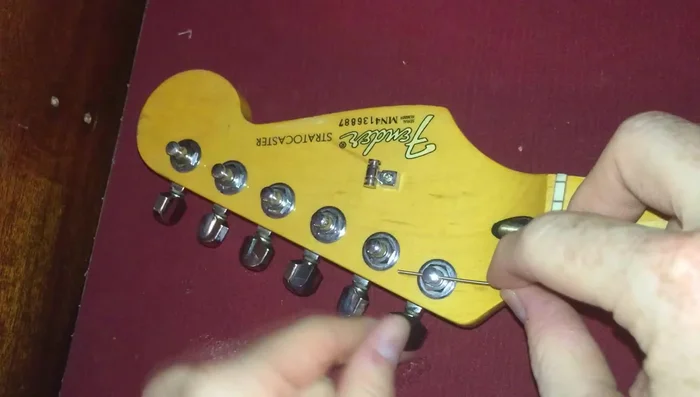 Push the string through the tuner post.