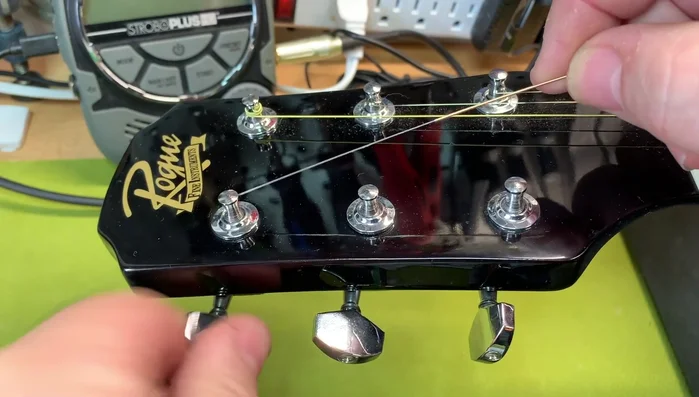 Feed the string through the holes, pulling it snug to remove slack from the bridge pin.