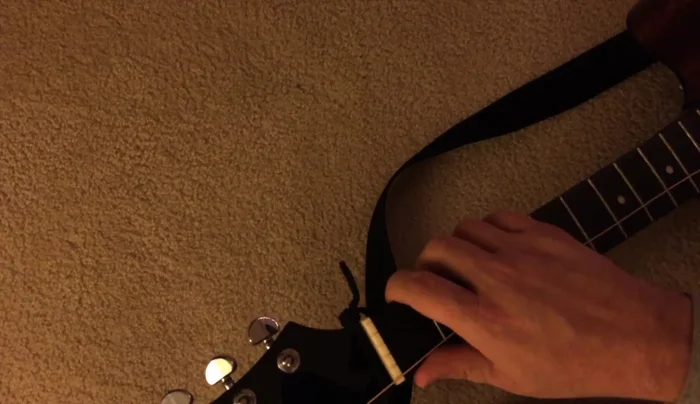 Wind the strings tightly around the tuning pegs, using finger pressure to control the wrapping.