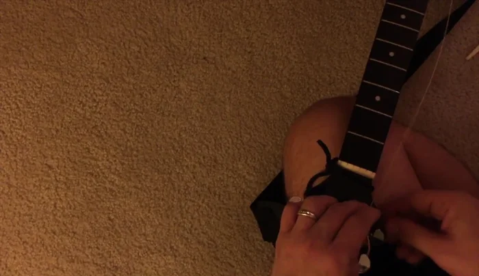 Wind the strings tightly around the tuning pegs, using finger pressure to control the wrapping.