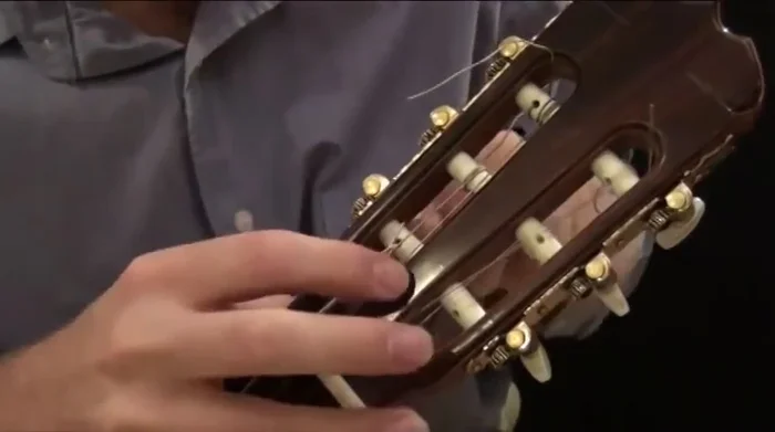 Tighten the string using the tuning peg, checking the tuning at the fifth fret to match the corresponding note on the fifth string.