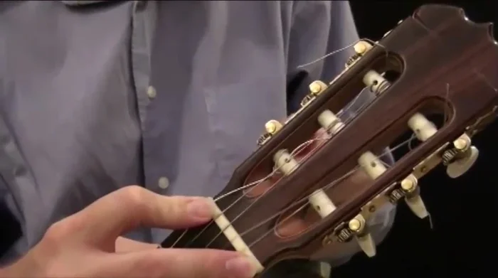 Tighten the string using the tuning peg, checking the tuning at the fifth fret to match the corresponding note on the fifth string.