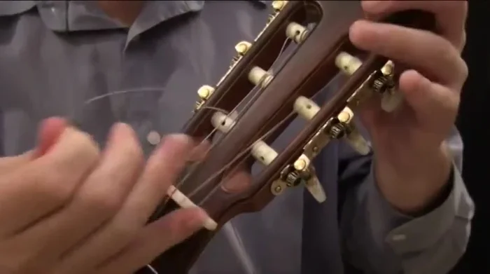 Remove the string from the bridge by slipping the loop forward and pulling it through.