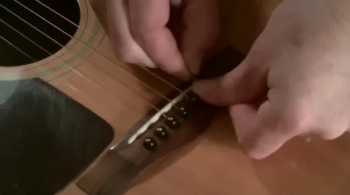 Insert the string into the tuning peg hole, ensuring the groove on the peg faces the string. Push it down and pull out as much string as possible.