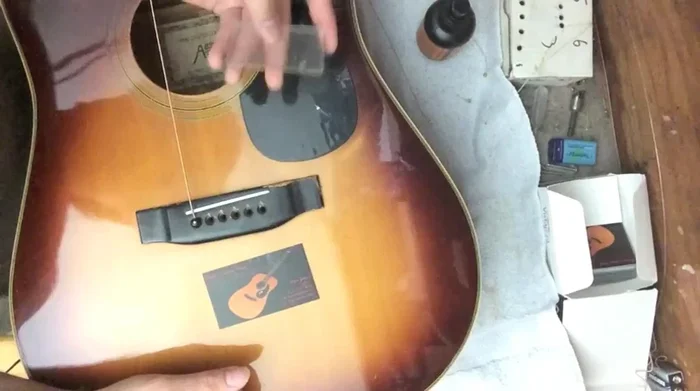 Apply pressure from inside the guitar using a flat block (like a 9V battery) against the bottom of the bridge pin.