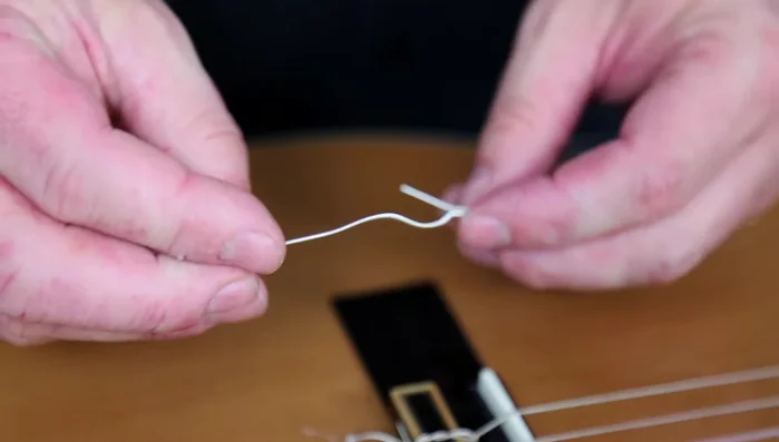 Make two knots in the string at the bridge.