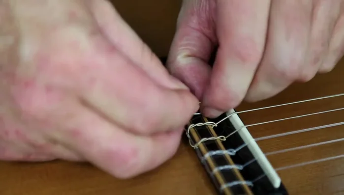 Make two knots in the string at the bridge.