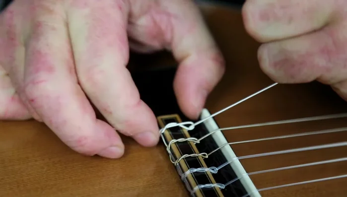 Wrap the excess string around the top of the wound string and feed it back down through the hole.