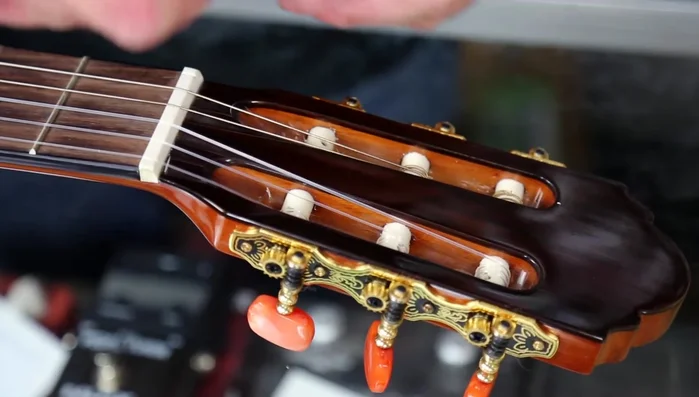 Wrap the excess string around the top of the wound string and feed it back down through the hole.