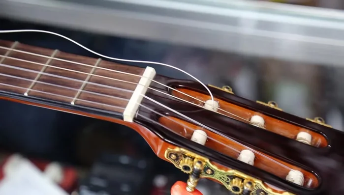 Wrap the excess string around the top of the wound string and feed it back down through the hole.