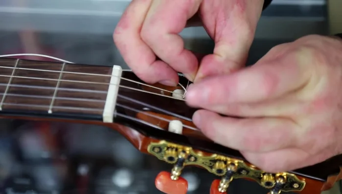 Wrap the excess string around the top of the wound string and feed it back down through the hole.